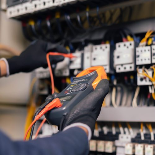Electrician engineer work tester measuring voltage and current of power electric line in electical cabinet control.and wires on relay protection system. Bay control unit. Medium voltage switchgear.